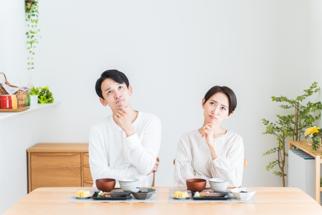 食卓で首を傾げる男女